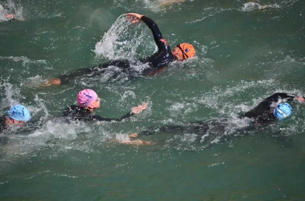 Auf dem Bild sind schwimmende Triathleten im Freiwasser zu sehen.